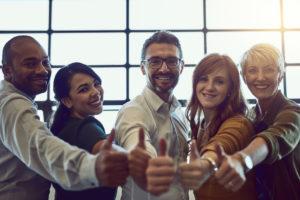 Portrait of a team of colleagues giving a thumbs up in a modern office