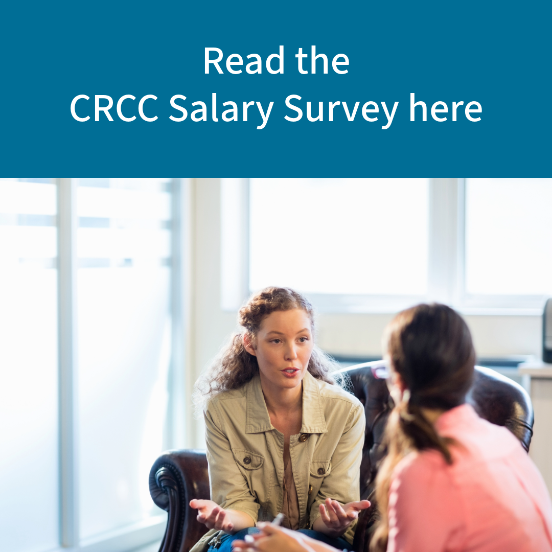 the image of a counselor with dark hair seated and speaking to a client, facing away from the camera, also with dark hair. Above, the text reads "read the CRCC salary survey here"