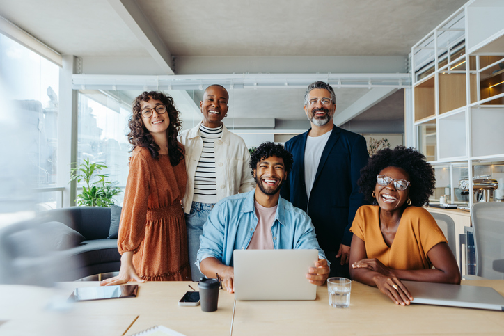 Successful business team working with a certified rehabilitation counselor together in an office. They are happy, smiling and looking at the camera, representing their thriving startup company.